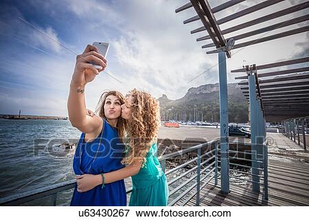 Two young women friends taking smartphone selfie on pier View Large Photo Image Stock Photo - Two young women friends taking smartphone selfie on pier. Fotosearch