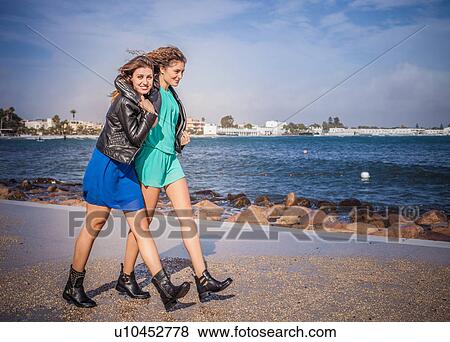 Two young women friends walking on promenade View Large Photo Image Stock Photo - Two young women friends walking on promenade. Fotosearch