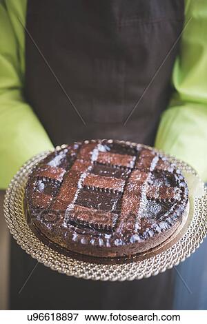 Stock Photo - Waiter carrying plate of chocolate cake. Fotosearch