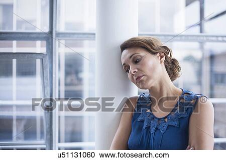 Stock Image - Woman leaning against pillar. Fotosearch