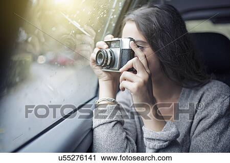 Stock Image - Woman photographing out of car window. Fotosearch