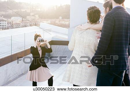 Woman taking photograph of friends at party View Large Photo Image Stock Image - Woman taking photograph of friends at party. Fotosearch