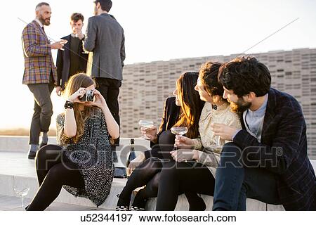 Woman taking photograph of friends at party View Large Photo Image Stock Photo - Woman taking photograph of friends at party. Fotosearch