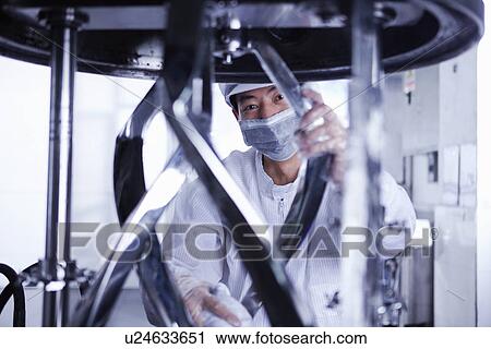 Stock Image - "Worker at e-cigarettes battery factory, Guangdong, China". Fotosearch