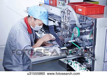 Stock Image - "Worker at e-cigarettes battery factory, Guangdong, China". Fotosearch