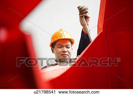 Stock Image - "Worker using equipment in crane manufacturing facility, China". Fotosearch
