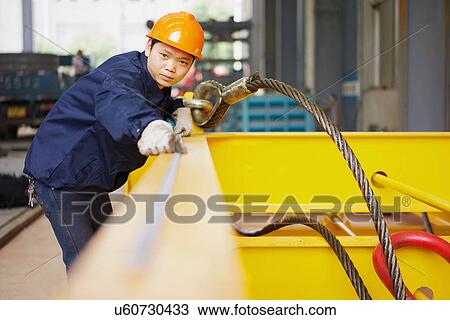 Stock Image - "Worker using equipment in crane manufacturing facility, China". Fotosearch