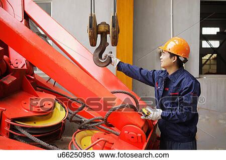 Stock Image - "Worker using equipment in crane manufacturing facility, China". Fotosearch
