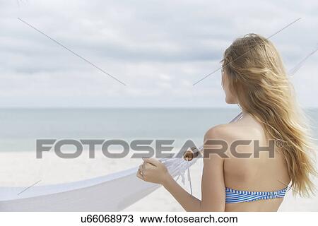 Stock Image - "Young blond woman looking out to sea from Miami Beach, Florida, USA". Fotosearch
