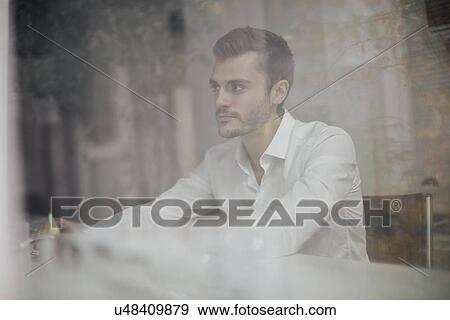 Stock Photo - Young businessman at desk through office window. Fotosearch