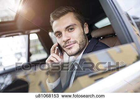Young businessman in taxi chatting on smartphone View Large Photo Image Stock Image - Young businessman in taxi chatting on smartphone. Fotosearch