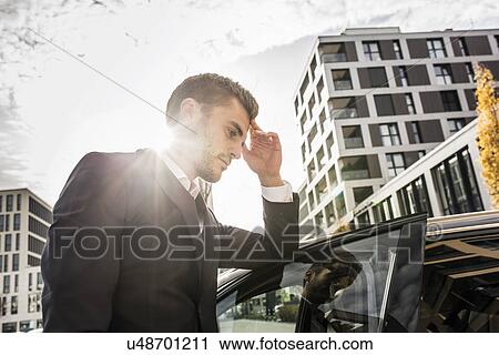 Young businessman leaning against car with hand on head View Large Photo Image Stock Image - Young businessman leaning against car with hand on head. Fotosearch