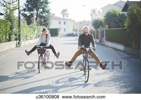 Young couple cycling with legs out View Large Photo Image Stock Photo - Young couple cycling with legs out. Fotosearch