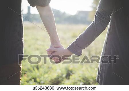 Stock Photograph - Young couple holding hands in sunlight. Fotosearch