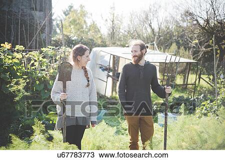 Young couple in garden holding fork and spade View Large Photo Image Stock Image - Young couple in garden holding fork and spade. Fotosearch