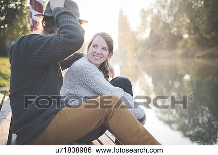 Stock Photograph - Young couple sitting by river. Fotosearch