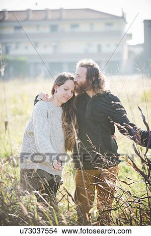 Picture - Young couple wearing touching plants in field. Fotosearch