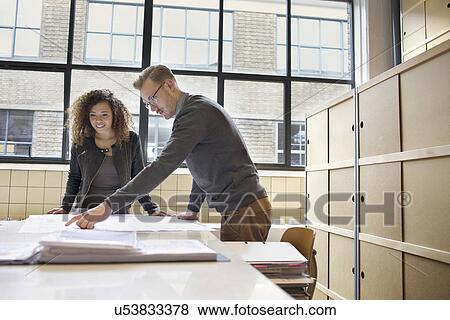 Young design team looking at blueprint in creative office View Large Photo Image Stock Photo - Young design team looking at blueprint in creative office. Fotosearch