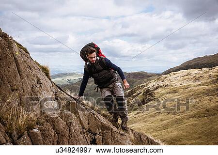 "Young male hiker stepping from rock, The Lake District, Cumbria, UK" View Large Photo Image Stock Photo - "Young male hiker stepping from rock, The Lake District, Cumbria, UK". Fotosearch
