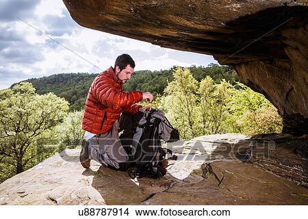 "Young male hiker unpacking backpack on crocodile rock, Pateley Bridge, Nidderdale, Yorkshire Dales" View Large Photo Image Picture - "Young male hiker unpacking backpack on crocodile rock, Pateley Bridge, Nidderdale, Yorkshire Dales". Fotosearch