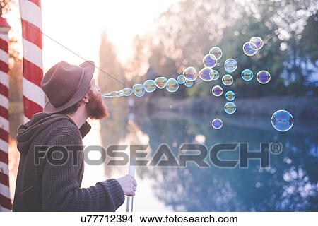 Picture - Young man blowing bubbles. Fotosearch