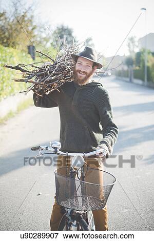Young man carrying bunch of sticks on shoulder on bike View Large Photo Image Stock Photo - Young man carrying bunch of sticks on shoulder on bike. Fotosearch