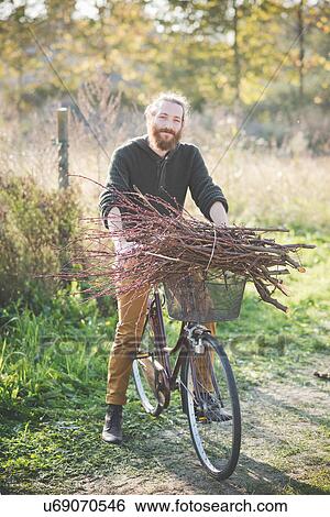 Young man carrying bunch of sticks on bicycle View Large Photo Image Stock Photograph - Young man carrying bunch of sticks on bicycle. Fotosearch