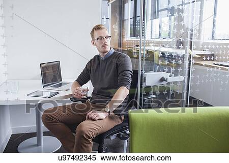 Stock Photography - Young man gazing from office desk. Fotosearch