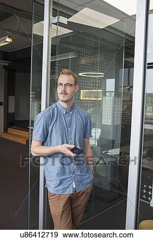 Stock Photo - Young man gazing from office doorway. Fotosearch
