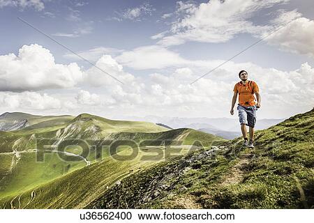 Stock Image - "Young man hiking on path, Saint-Michel, Pyrenees, France (Near the Spanish-French border)". Fotosearch