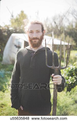 Young man in garden holding fork View Large Photo Image Stock Photo - Young man in garden holding fork. Fotosearch