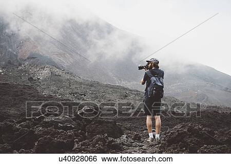 Stock Photograph - "Young man photographing the Pacaya volcano, Antigua, Guatemala". Fotosearch