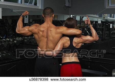Stock Photo - "Young woman and mid adult man, flexing muscles, rear view". Fotosearch