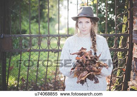 Stock Photography - Young woman collecting autumn leaves. Fotosearch