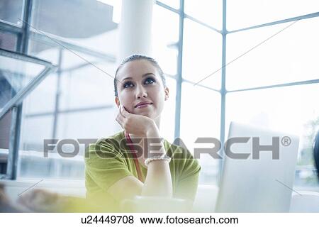 Stock Photo - Young woman day dreaming in office. Fotosearch