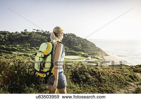 Stock Photo - "Young woman hiking on coastal path, Erretegia beach, Bidart, France". Fotosearch