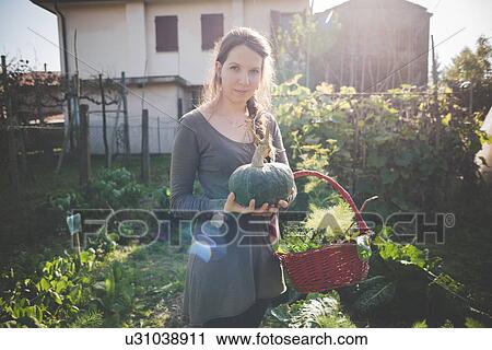 Young woman holding homegrown squash View Large Photo Image Stock Image - Young woman holding homegrown squash. Fotosearch