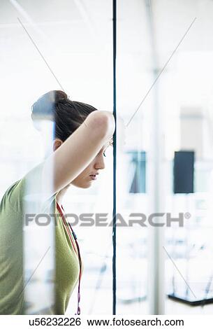 Stock Photograph - Young woman leaning head on glass wall. Fotosearch