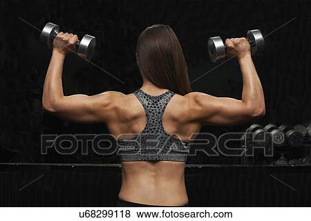 Stock Photo - "Young woman, lifting weights, rear view". Fotosearch