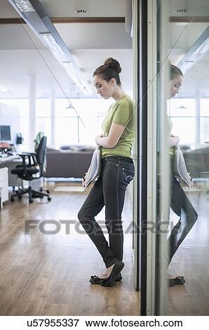 Stock Photo - Young woman looking glum against glass door. Fotosearch