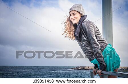 Stock Photo - Young woman looking out from sea pier. Fotosearch