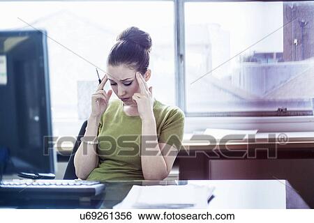 Young woman looking worried at her desk View Large Photo Image Stock Photograph - Young woman looking worried at her desk. Fotosearch