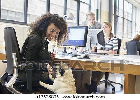 Young Woman Petting Dog At Office Desk Stock Photography