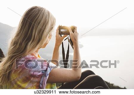 Stock Image - "Young woman photographing at Lake Atitlan on digital camera, Guatemala". Fotosearch