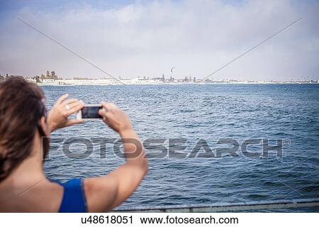 Young woman photographing sea view on smartphone View Large Photo Image Stock Image - Young woman photographing sea view on smartphone. Fotosearch