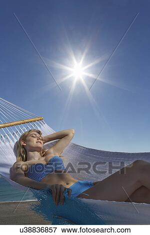 Stock Photo - "Young woman reclining on hammock in sunlight on Miami Beach, Florida, USA". Fotosearch