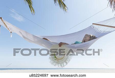 Stock Photo - "Young woman reclining on hammock on Miami Beach, Florida, USA". Fotosearch
