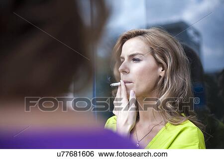 Young woman smoking cigarette outside office building View Large Photo Image Stock Photograph - Young woman smoking cigarette outside office building. Fotosearch