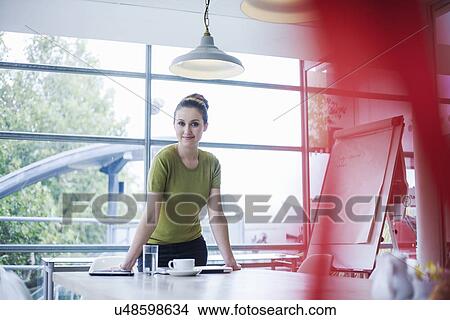 Young woman standing at meeting room table View Large Photo Image Picture - Young woman standing at meeting room table. Fotosearch