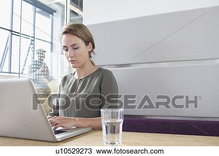 Young woman typing on laptop in office View Large Photo Image Stock Image - Young woman typing on laptop in office. Fotosearch